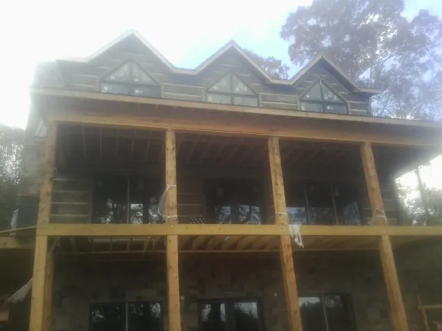 Dormers and porch framing on a large log home under construction — Roof Coating work by our crew in Percival