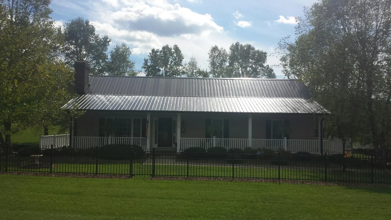 Gray metal roof on a brick ranch with a full width front porch — Gutter Guard Installation work by our crew in Percival