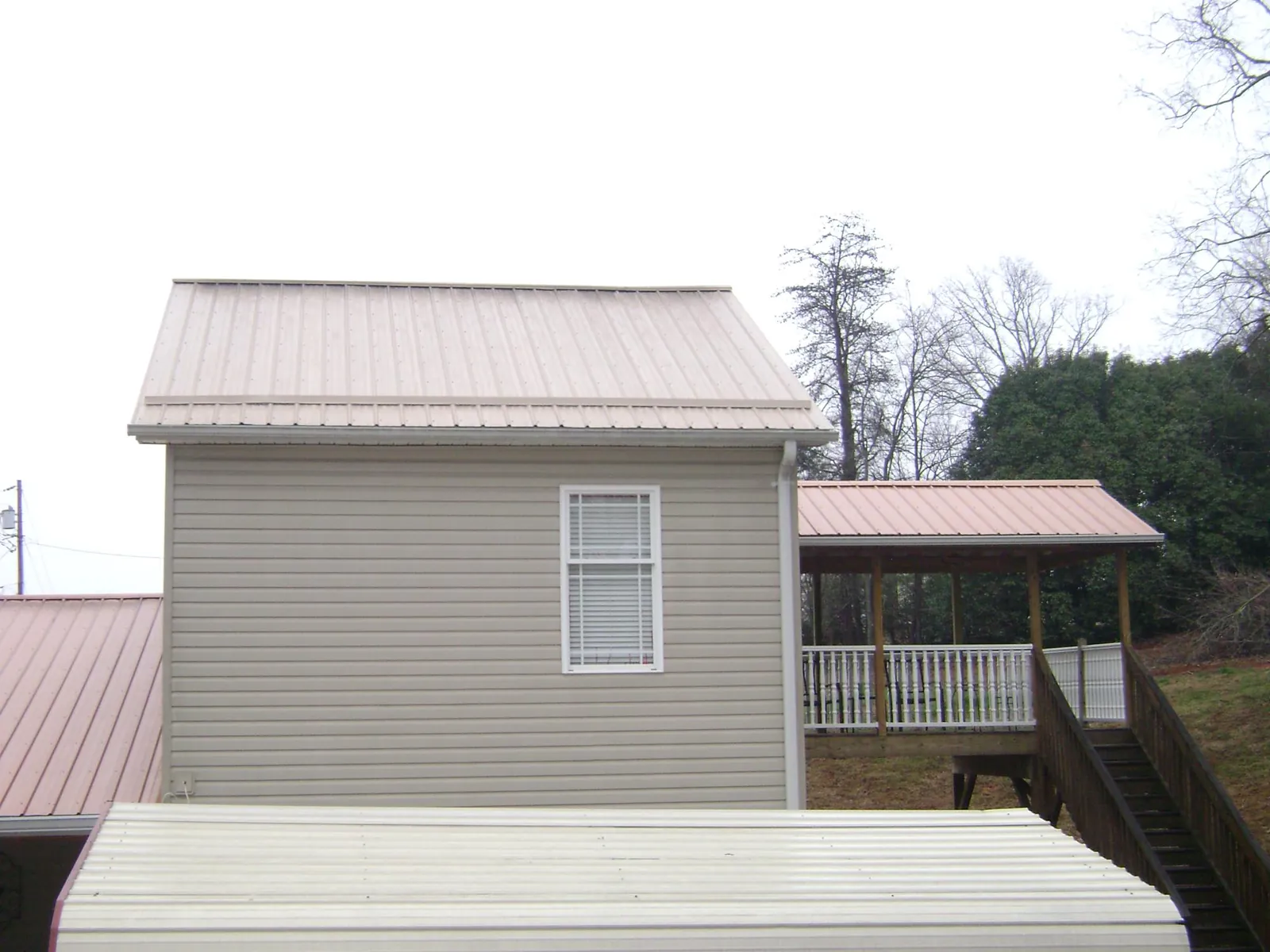 Tan metal roofs on a two story addition and attached porch, from a Roof Replacement job in Percival