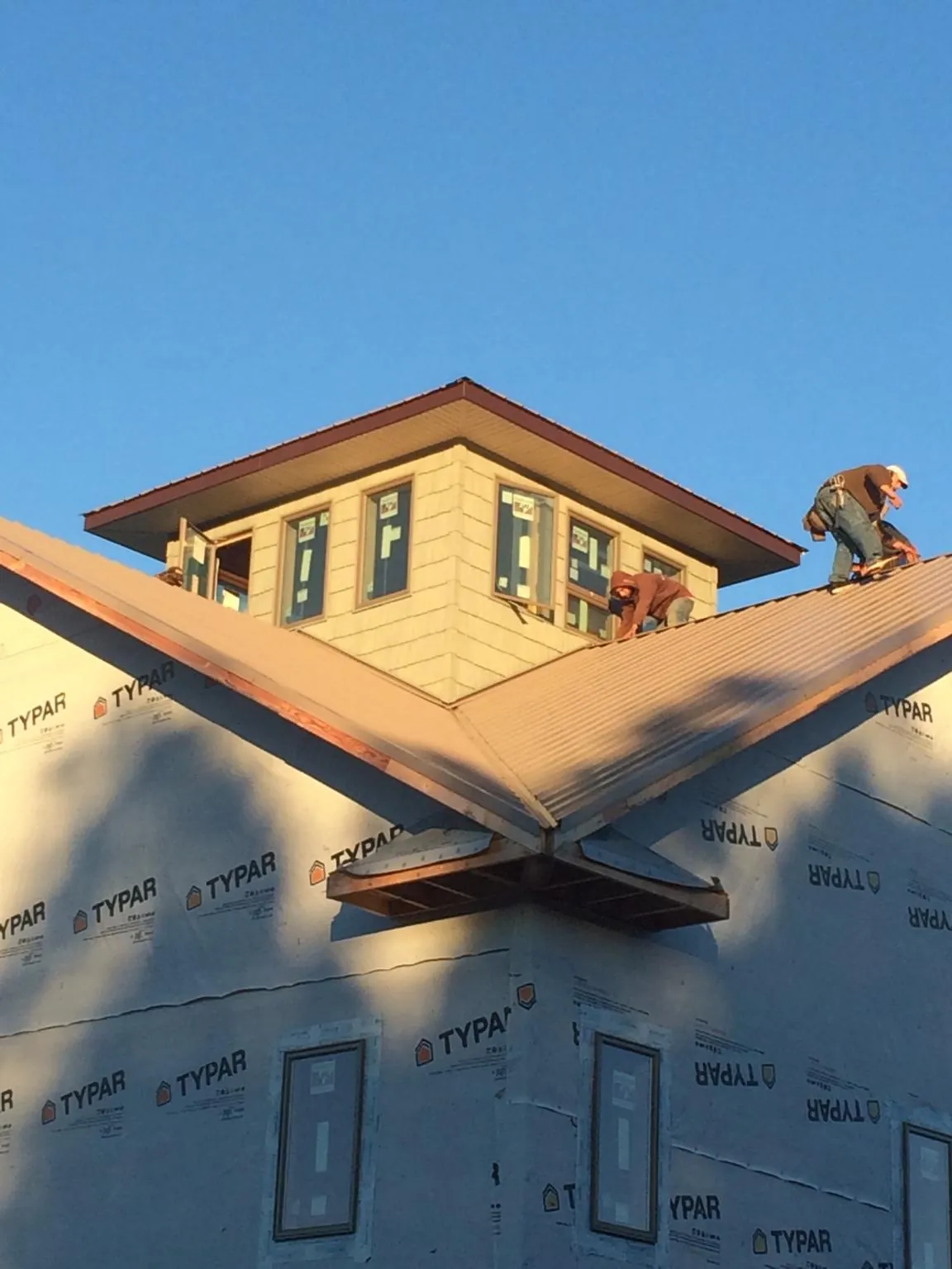 Roofers working around a rooftop cupola on a new metal roof at sunset — Roof Waterproofing in Percival by Roofing Brothers